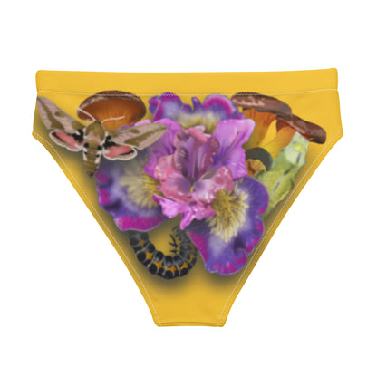 Yellow bikini bottom showcasing a flower in the center, surrounded by mushrooms. In it, a moth, cocoon, and caterpillar appear in a triad.